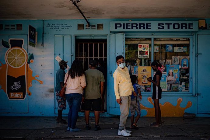 Archivo - 14 October 2021, Mauritius, Baie Du Cap: People wait to be served outside a local store in the small fishing village of Baie Du Cap.