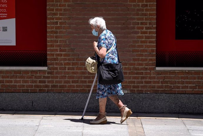 Archivo - Una mujer mayor con mascarilla camina sola por la calle.