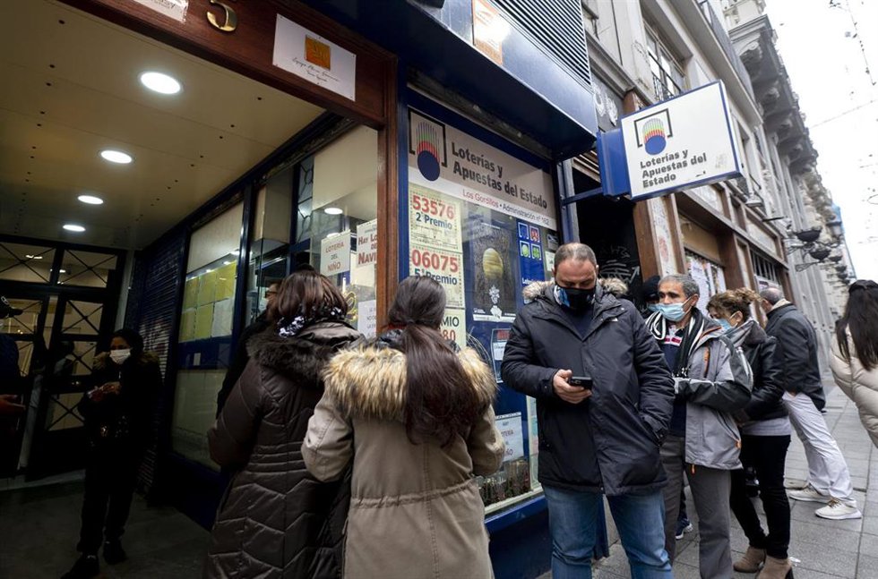 Varias personas hacen cola en una administración de Loterías del centro de Madrid. 