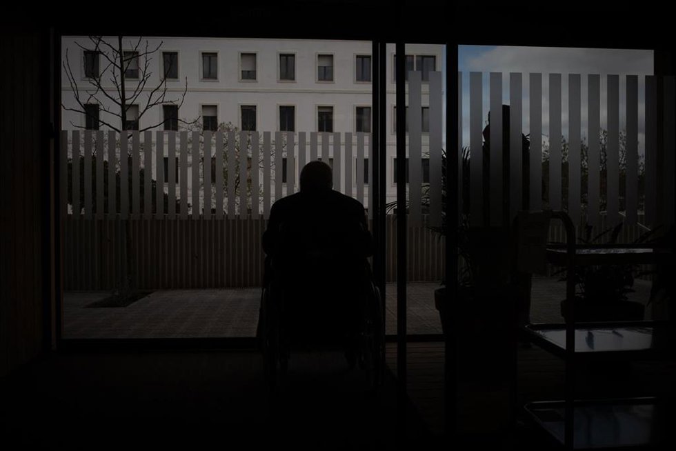 Archivo - Un hombre en silla de ruedas observa el exterior del edificio Garbí-Vall de Hebrón, en Barcelona.