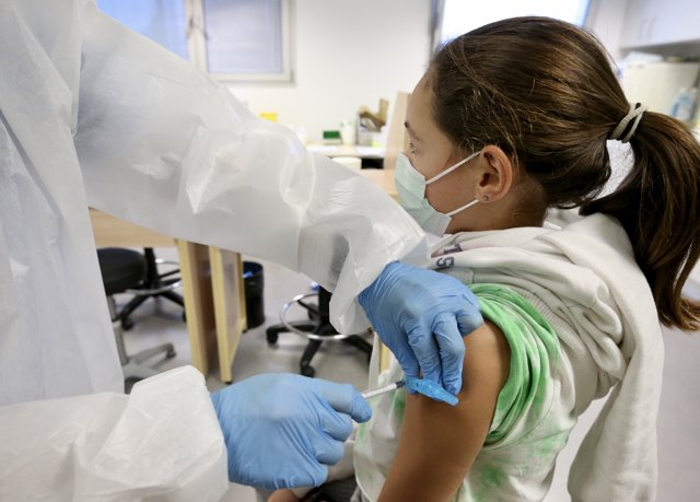 Una sanitaria administra la primera dosis de la vacuna a una niña en el centro de salud El Alisal