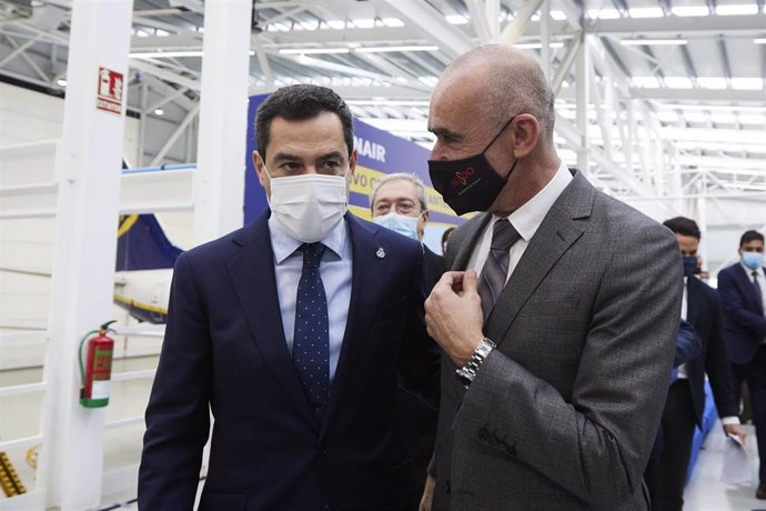 El presidente de la Junta, Juanma Moreno, (i) dialoga con el Teniente de Alcalde del Sevilla, Antonio Muñoz, (d) durante la inauguración del nuevo Hangar de Ryanair en Sevilla.