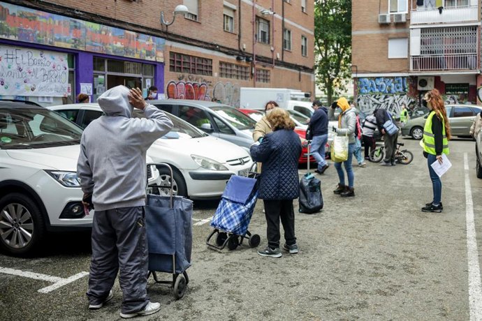 Archivo - Vecinos realizan una cola para recoger bolsas de alimentos durante la pandemia.