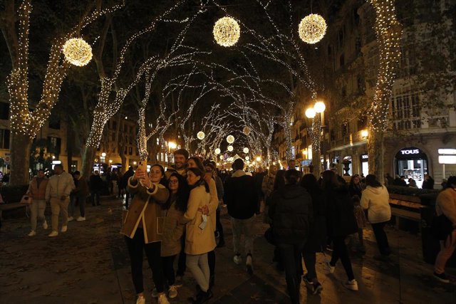 Un grupo de personas se fotografía con el encendido de las luces de Navidad en Palma.