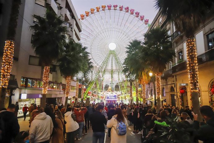 Personas en la calle, disfrutando del alumbrado navideño y la gran noria en el centro de Vigo (Pontevedra).