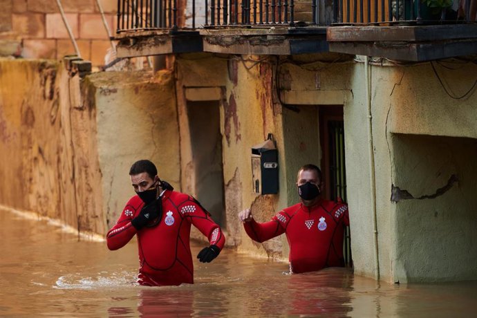 Trabajadores de Protección Civil caminan por una calle inundada, a 12 de diciembre de 2021, en Tudela.