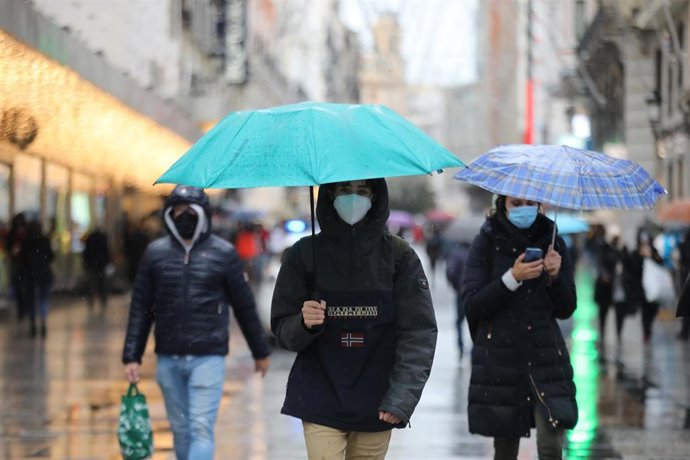 Archivo - Transeúntes pasean protegidos con paraguas por el centro de la capital, en Madrid, (España)