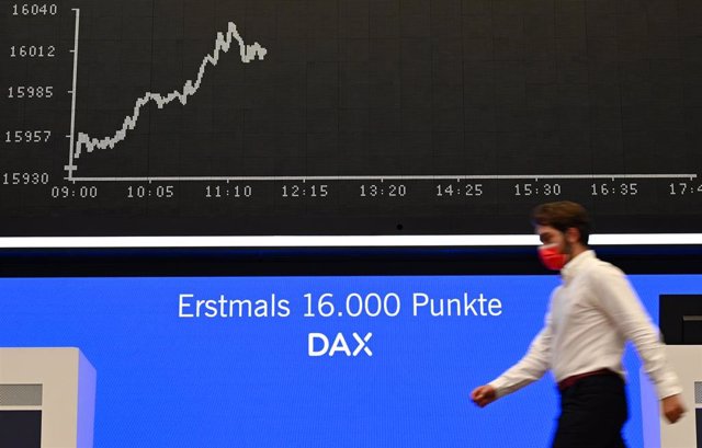 Archivo - 13 August 2021, Hessen, Frankfurt_Main: A stock exchange trader walks past a board showing the DAX Curve at the trading room of the Frankfurt Stock Exchange. DAX hit a record high of above 16,000 points for the first time ever. Photo: Arne Deder