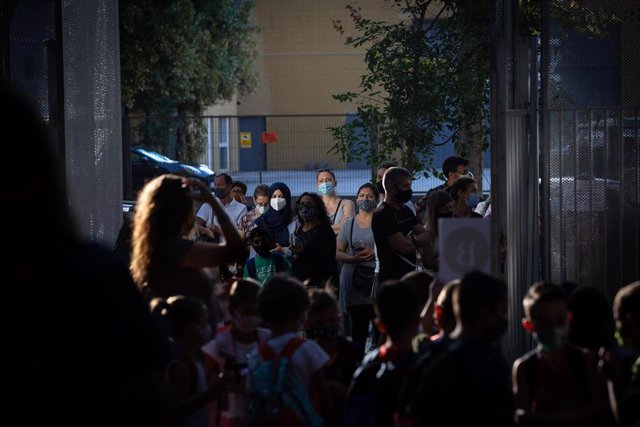 Archivo - Padres y alumnos esperan a las puertas de un colegio en Barcelona.