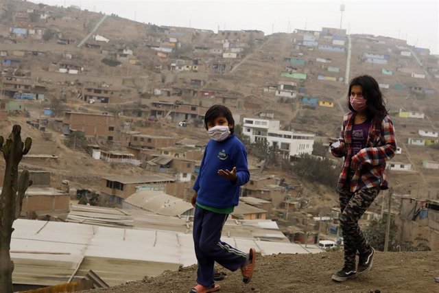 Archivo - Dos niños con mascarilla caminan por la barriada de Villa Maria del Triunfo, Lima, durante la pandemia de coronavirus