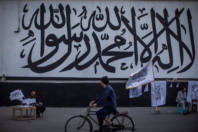 Archivo - Un hombre vende banderas de los talibán frente al muro de la antigua Embajada de EEUU en la capital de Afganistán, Kabul, ahora cubierta con un mural religioso