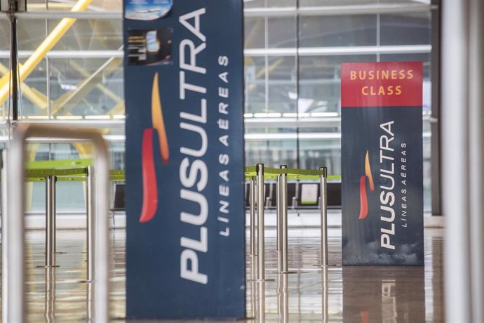 Archivo - Un panel muestra información sobre vuelos de la aerolínea Plus Ultra, en el aeropuerto de Madrid.