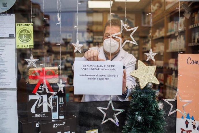 El farmacéutico cuelga el cartel de que los test de antígenos de la Comunidad de Madrid están agotados en la farmacia de la Calle Tucán, en el distrito de Carabanchel, a 21 de diciembre de 2021, en Madrid (España). 