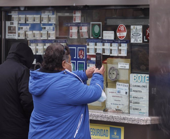 Varias personas en una administración de lotería de Navidad de la Puerta del Sol cuando quedan menos de tres semanas para el Sorteo Extraordinario de la Lotería de Navidad, a 7 de diciembre de 2021, en Madrid (España). Como cada año, la Lotería de Navid