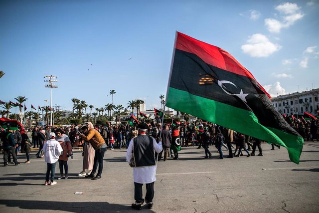 Archivo - Un hombre ondea la bandera libia en Trípoli