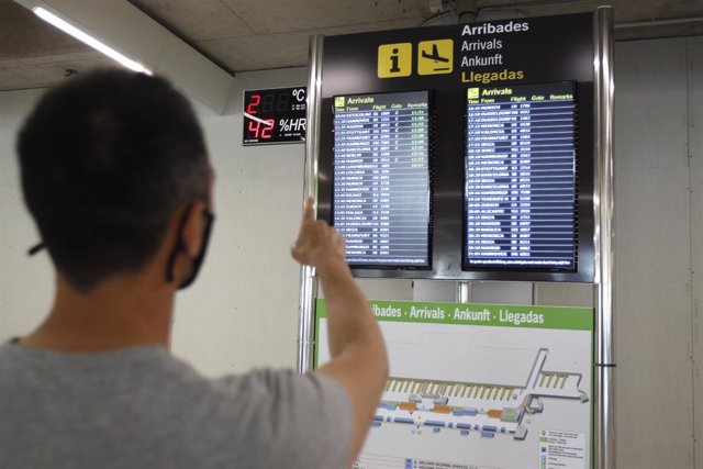Archivo - Un pasajero señala la pantalla del aeropuerto de Palma.