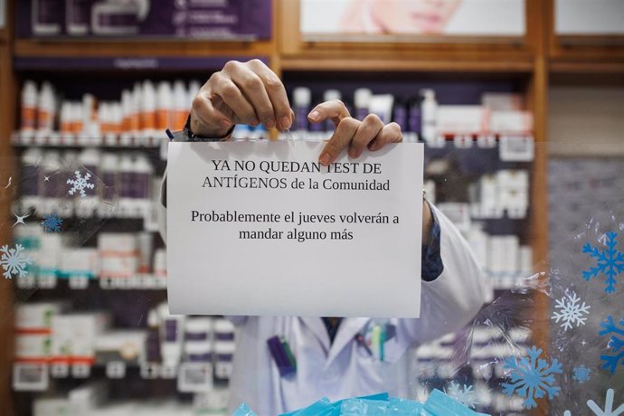 El farmacéutico cuelga el cartel de que los test de antígenos de la Comunidad de Madrid están agotados en la farmacia de la Calle Tucán, en el distrito de Carabanchel, a 21 de diciembre de 2021, en Madrid (España).