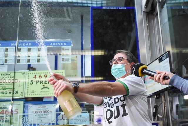 Javier Moñino, empleado de la administración situada en la zona del AVE de la Estación de Atocha, abre una botella para celebrar que ha vendido parte del número 86148 correspondiente al  'Gordo'