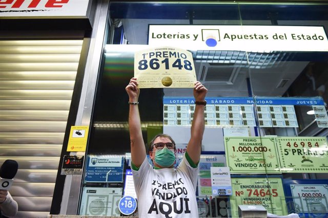 Javier Moñino, empleado de la administración situada en la zona del AVE de la Estación de Atocha, celebra que ha vendido parte del número 86148 correspondiente al  'Gordo' del Sorteo Extraordinario de la Lotería de Navidad, a 22 de diciembre de 2021, en M