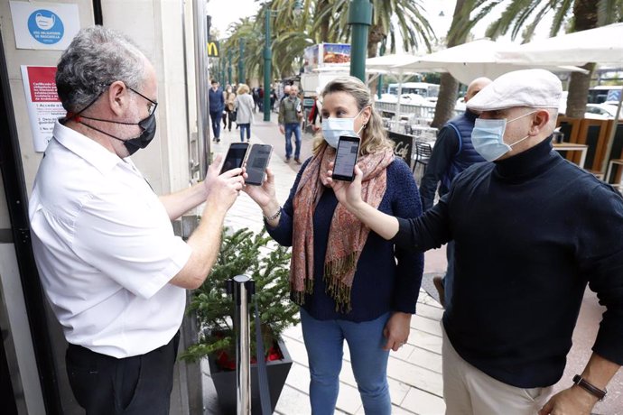 Un camarero pide certificado a los clientes en la puerta de un bar durante el primer día de petición de Certificados Covid-19 para la hostelería, a 20 de diciembre de 2021 en Málaga (Andalucía, España)