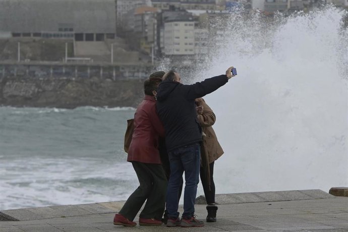 Un grupo de personas se hace una fotografía en la zona de las Esclavas, a 8 de diciembre de 2021, en A Coruña, Galicia, (España). La borrasca Barra ha hecho que la Xunta haya activado para todo el litoral gallego una alerta naranja por temporal costero.