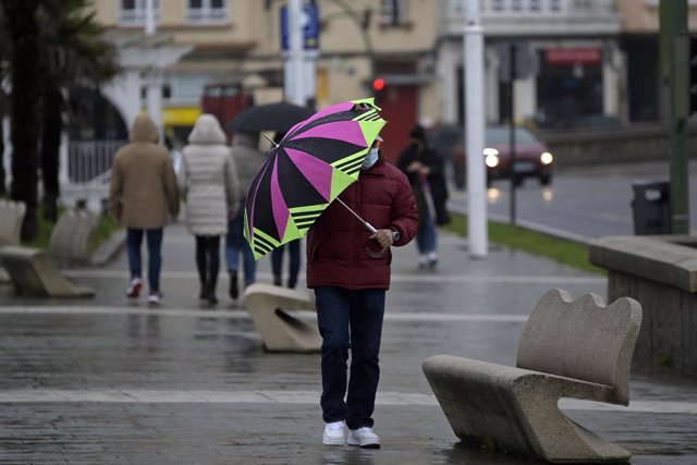 Un hombre con un paraguas camina por el paseo marítimo mientras llueve, a 8 de diciembre de 2021, en A Coruña, Galicia, (España). La borrasca Barra ha hecho que la Xunta haya activado para todo el litoral gallego una alerta naranja por temporal costero. S