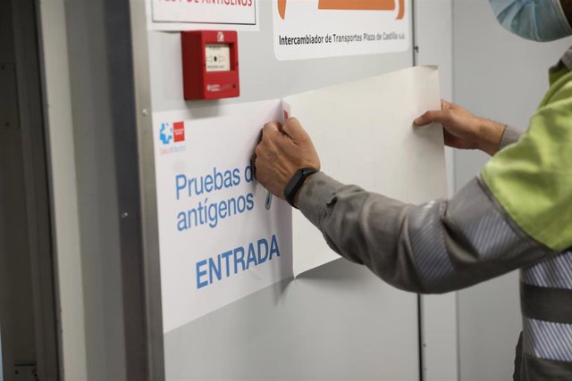 Archivo - Un hombre pone un cartel que indica la entrada de realización de test de antígenos