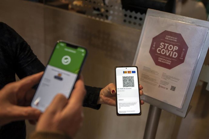 Una persona muestra su pasaporte Covid al entrar en un local