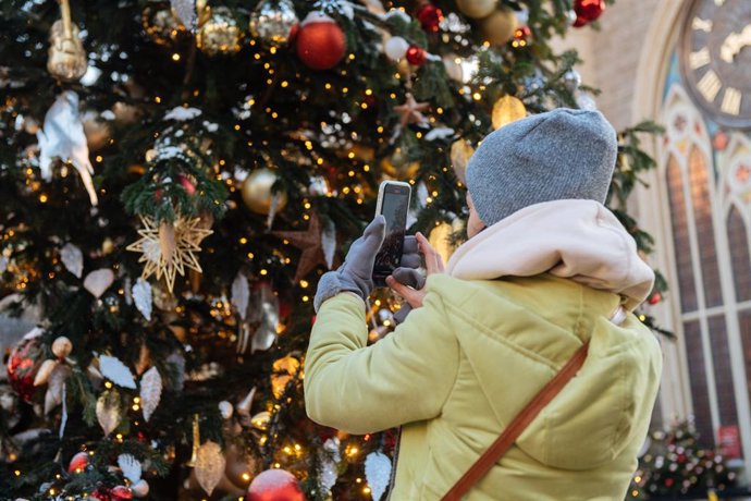 Una mujer fotografiando un árbol de Navidad