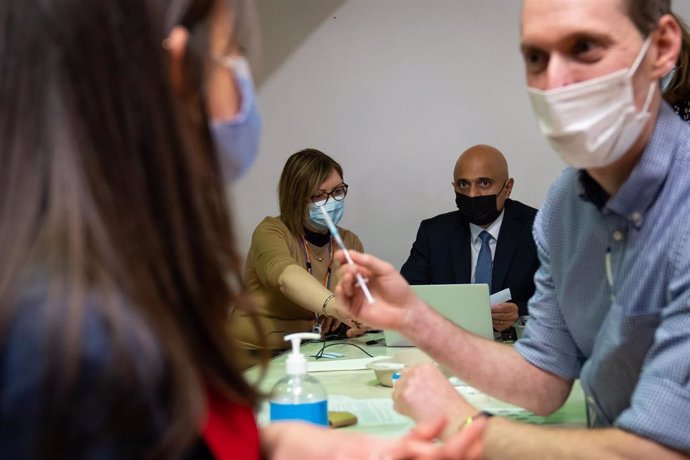 02 December 2021, United Kingdom, London: UK Health Secretary Sajid Javid helps fill in patient data for Amie Stott, who is receiving her booster vaccine, during a visit to Abbey vaccine centre in central London. Photo: Aaron Chown/PA Wire/dpa