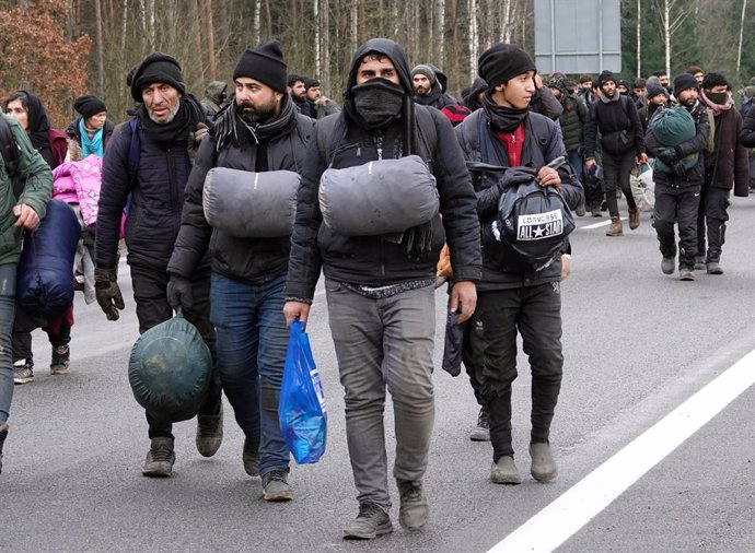Archivo - 18 November 2021, Belarus, Brusgi: Migrants carry their belongings to a warehouse near the border between Belarus and Poland. Around 900 migrants on the border with Poland have spent the night from Wednesday to Thursday outdoors for the 11th c