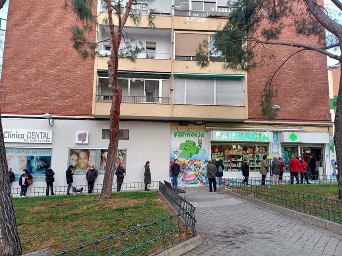 Cola de personas para recoger un test de antígenos en una farmacia del Barrio del Pilar
