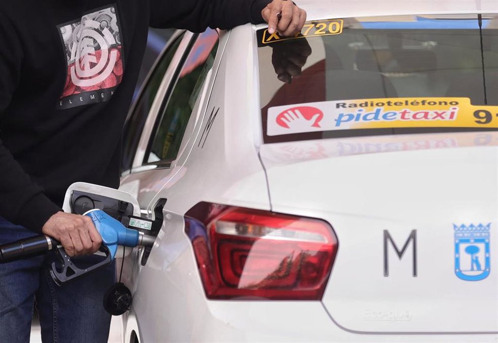Archivo - Un hombre inyecta carburante a un taxi