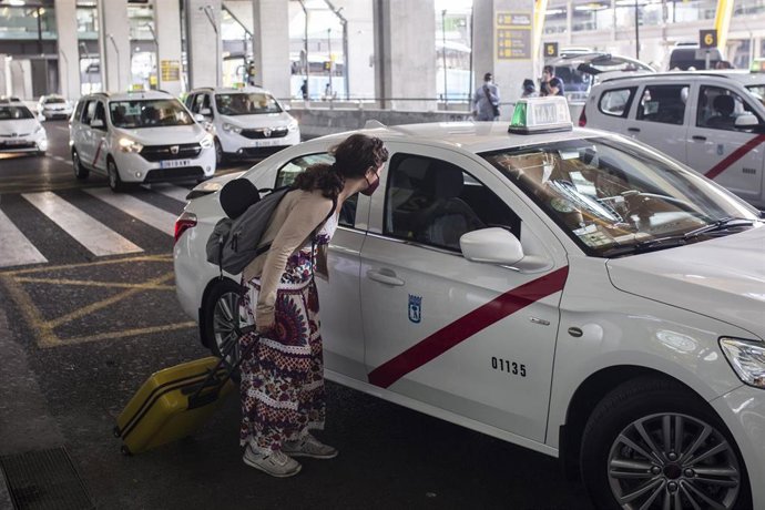 Archivo - Una pasajera conversa con un taxista en las inmediaciones de la Terminal T4  del Aeropuerto Adolfo Suárez Madrid-Barajas, a 7 de junio de 2021, en Madrid, (España). España permite desde este lunes la entrada de viajeros que acrediten estar vac