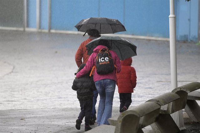 Un grupo de personas camina por el paseo marítimo mientras llueve, a 8 de diciembre de 2021, en A Coruña, Galicia, (España). La borrasca Barra ha hecho que la Xunta haya activado para todo el litoral gallego una alerta naranja por temporal costero. Según 