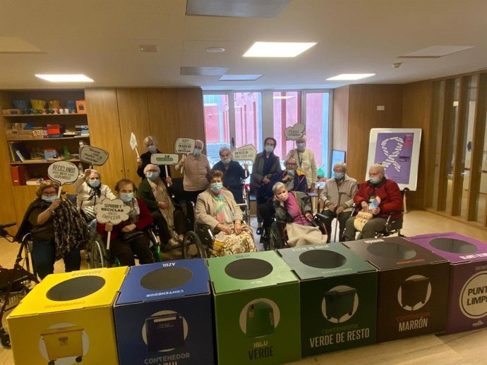 Personas mayores en una residencia con papeleras de separación de residuos