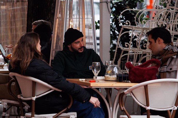 Tres amigos toman el aperitivo en la calle de Ponzano para celebrar la llegada de la Nochebuena, a 24 de diciembre de 2021, en Madrid (España). A pesar de las nuevas restricciones, como el uso de la mascarilla en exteriores, que entra en vigor hoy, vari