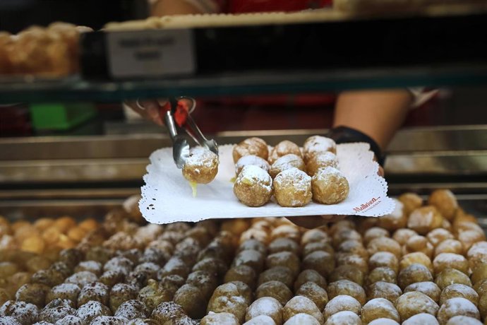 Archivo - Una trabajadora coloca una bandeja de buñuelos de viento en la Pastelería Mallorca, en Madrid, (España).