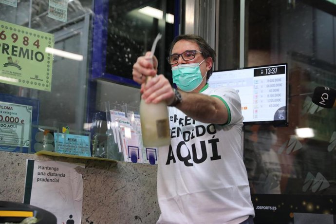 Javier Moñino, empleado de la administración situada en la zona del AVE de la Estación de Atocha, abre una botella para celebrar que ha vendido parte del número 86148 correspondiente al  'Gordo' del Sorteo Extraordinario de la Lotería de Navidad, a 22 d