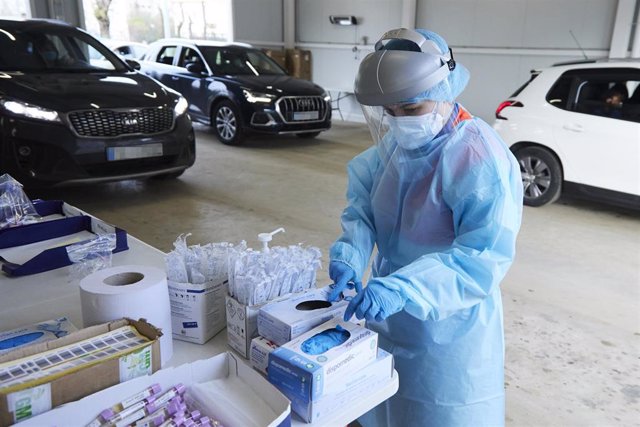 Una sanitaria se cambia los guantes tras realizar la prueba durante la realización de PCR en el autocovid instalado en el Hospital Militar