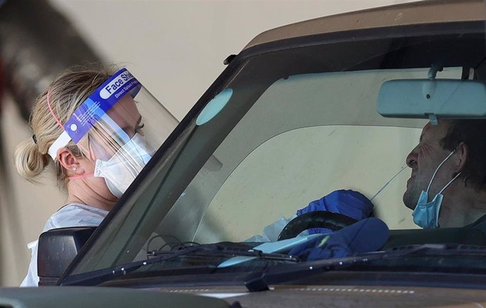 29 December 2021, Australia, Melbourne: A health worker takes a swab for a COVID-19 test from a man in his car at a drive-through COVID-19 testing site at IPC Health Wyndham Vale in Melbourne. 