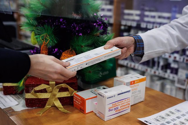 Una persona recoge un test de antígenos en una farmacia.