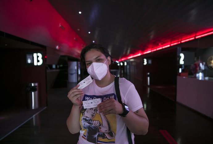 Archivo - Una mujer muestra su entrada a la cámara en una foto de archivo.
