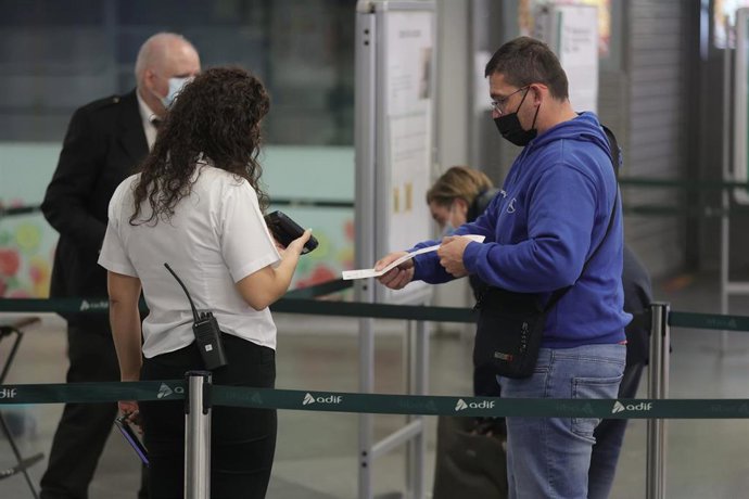 Archivo - Un pasajero pasa su billete por el control para acceder a un tren en la estación de Atocha