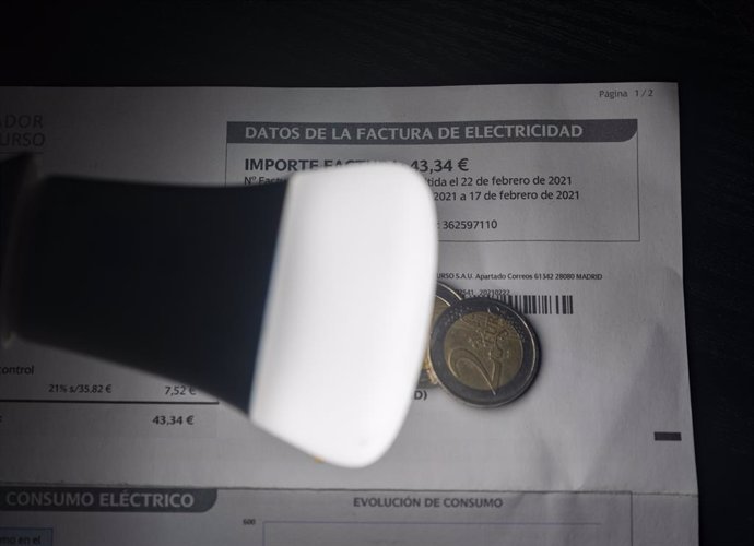 Una lámpara refleja el importe de una factura el día en que el precio de la luz ha marcado un mínimo por primera vez en dos meses, a 27 de diciembre de 2021, en Madrid, (España). El precio medio de la electricidad en el mercado mayorista registra una ba