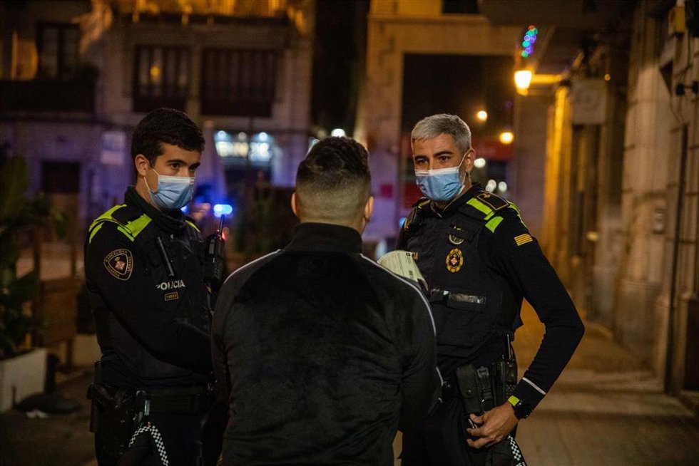 Una pareja de la Guardia Urbana multa a una persona tras la entrada en vigor del toque de queda, a 24 de diciembre de 2021, en Barcelona, Catalunya (España).