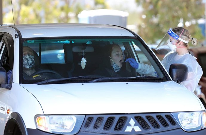 29 December 2021, Australia, Melbourne: A health worker takes a swab for a COVID-19 test from a woman in her car at a drive-through COVID-19 testing site at IPC Health Wyndham Vale in Melbourne. Photo: Con Chronis/AAP/dpa