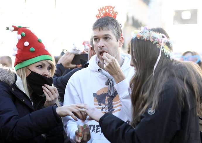Tres personas se comen las uvas en la celebración del simulacro de las preuvas, en la Puerta del Sol, a 30 de diciembre de 2021, en Madrid, (España). El Ayuntamiento de Madrid ha reducido a 7.000 personas el aforo en la Puerta del Sol para celebrar las 