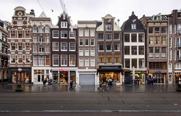 19 December 2021, Netherlands, Amsterdam: People walk past shops in the city centre. A hard lockdown has started in the Netherlands just before Christmas because of the omicron variant of the coronavirus. Photo: Ramon Van Flymen/ANP/dpa