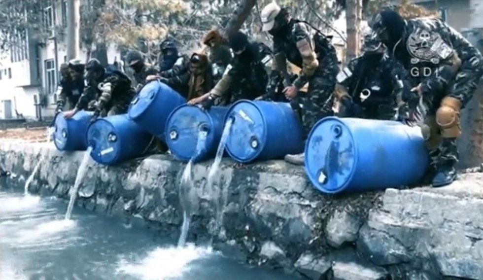 Agentes afganos vertiendo alcohol incautado en un canal de Kabul